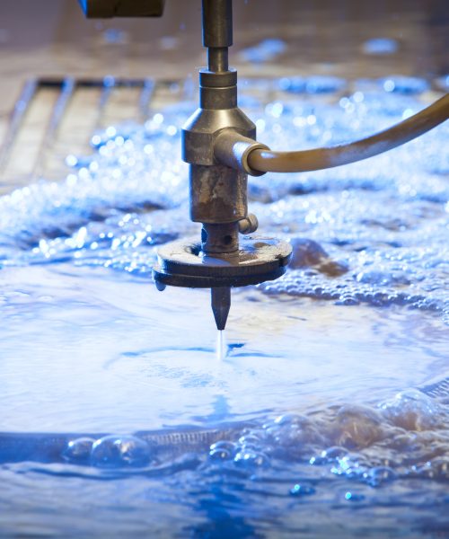 Waterjet cutting nozzle  close-up from metalwork industry. CNC waterjet machine at work cutting a steel plate.